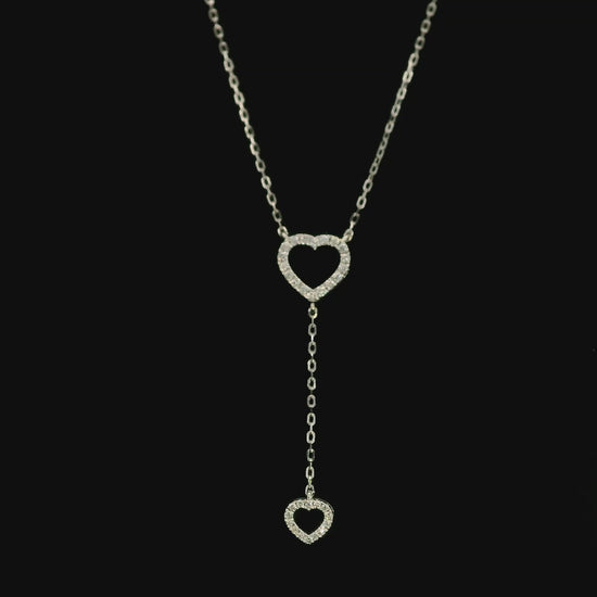 Diamond double heart Y necklace in 18K white gold featuring a larger open diamond heart at the neckline and a smaller diamond heart suspended from a delicate vertical drop chain, with 0.23 carat total diamond weight.