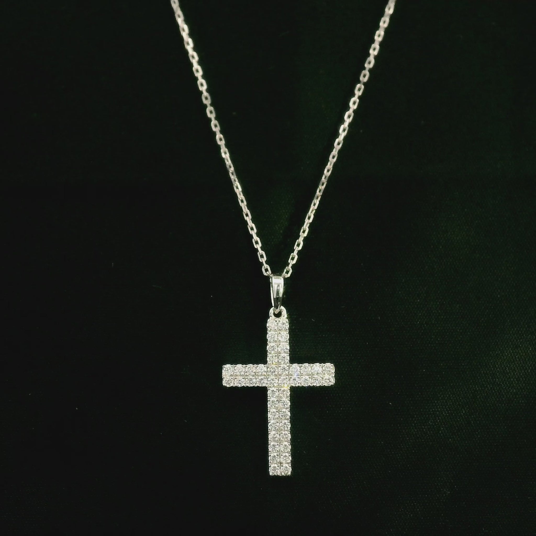 Diamond cross pendant in 18K white gold featuring a traditional cross design covered with multiple rows of round diamonds totalling 0.62 carat, shown on a chain for display.