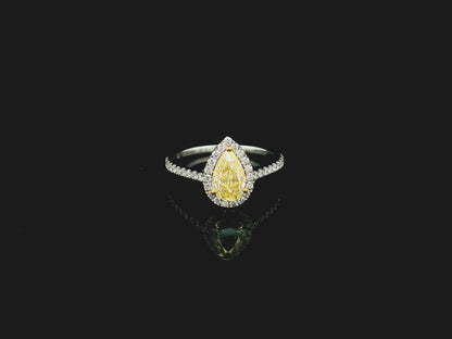 Fancy yellow pear-shaped diamond halo ring in 18K white gold with pavé diamond band and GIA certified center stone.
