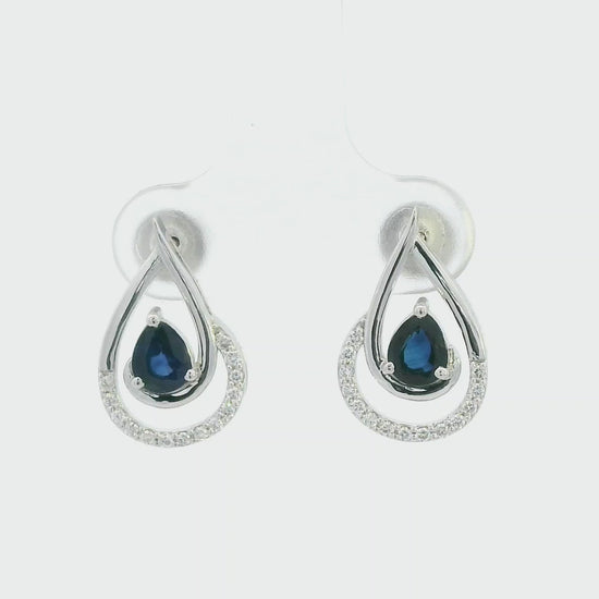 Blue sapphire and diamond stud earrings in 18K white gold with pear-cut sapphires and pavé diamond accents by Emirates Diamonds