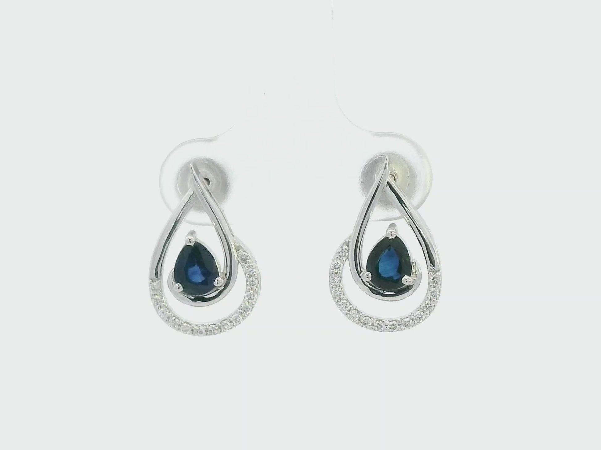 Blue sapphire and diamond stud earrings in 18K white gold with pear-cut sapphires and pavé diamond accents by Emirates Diamonds