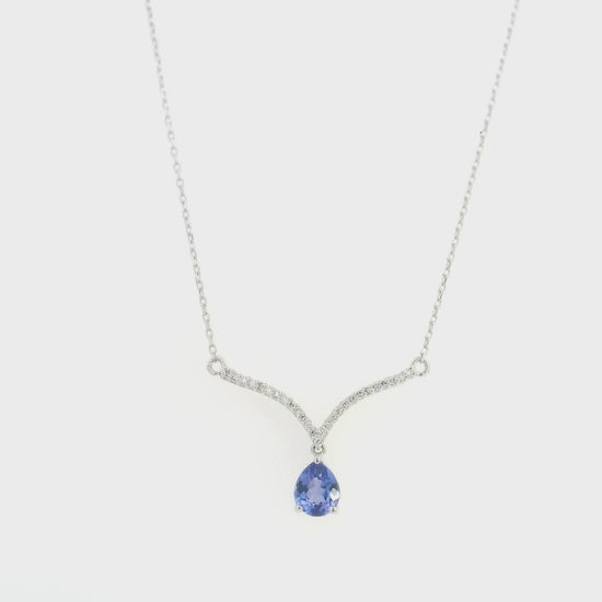 Pear shaped tanzanite and diamond necklace in 18K white gold featuring a blue-violet tanzanite drop suspended beneath two curved diamond-set bars forming a V-shaped design.