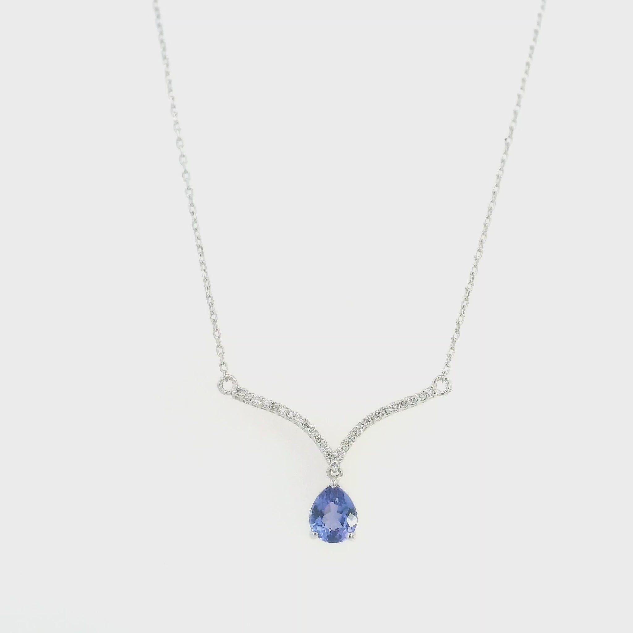 Pear shaped tanzanite and diamond necklace in 18K white gold featuring a blue-violet tanzanite drop suspended beneath two curved diamond-set bars forming a V-shaped design.