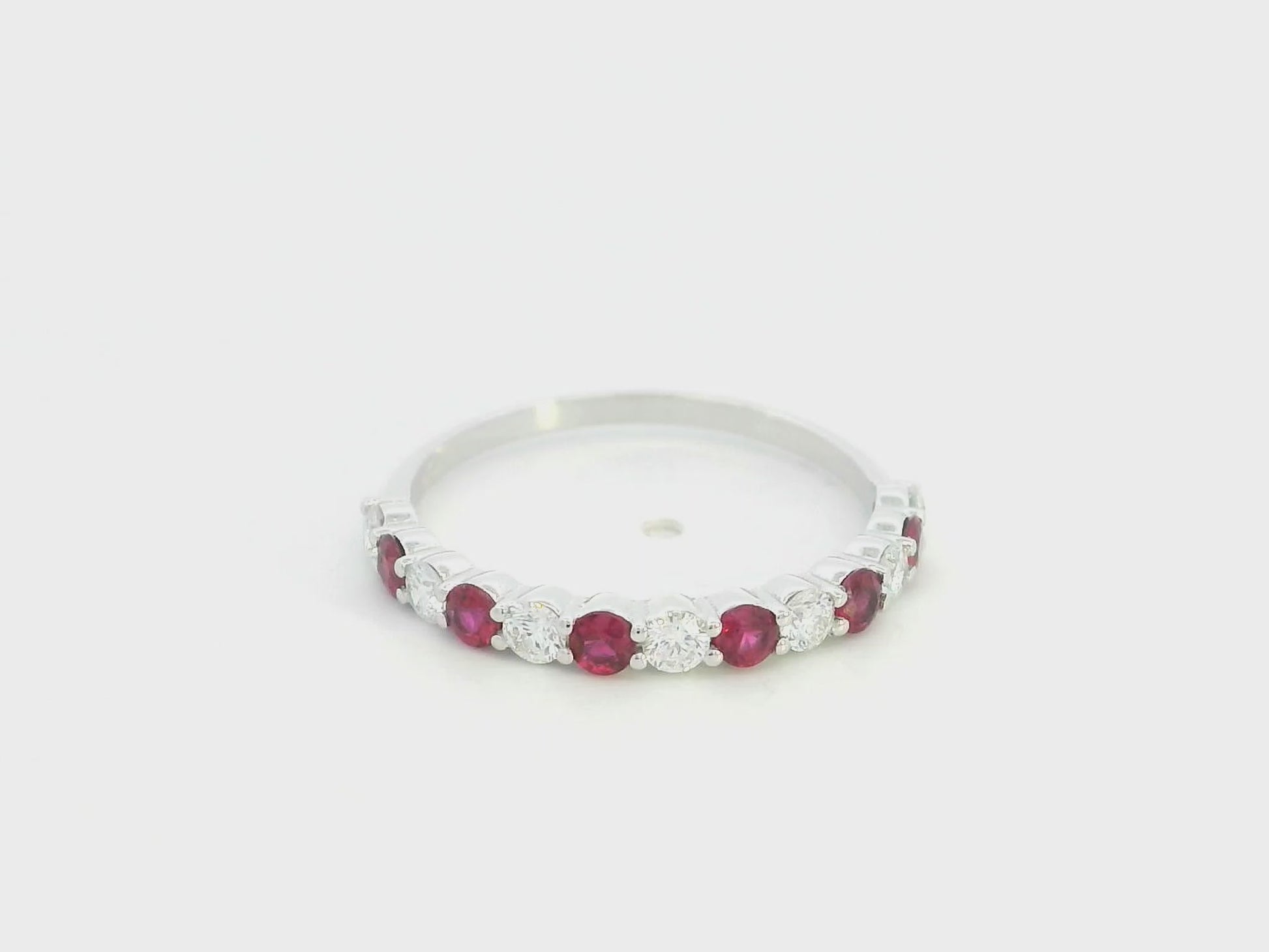 Ruby and diamond half eternity ring in 18K white gold with alternating round rubies and diamonds.