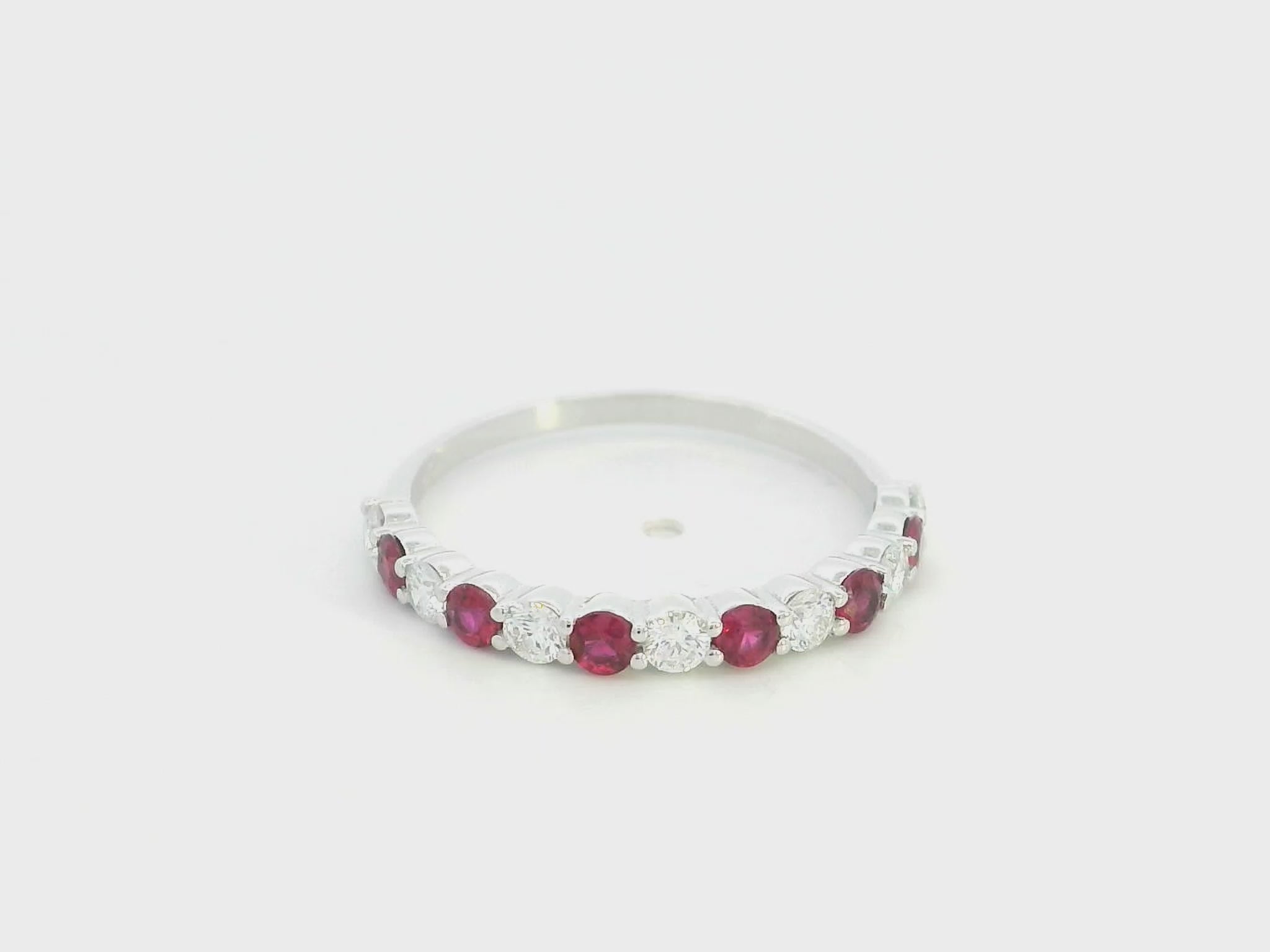 Ruby and diamond half eternity ring in 18K white gold with alternating round rubies and diamonds.