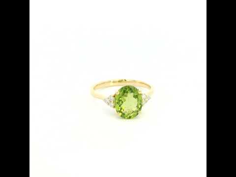 18K yellow gold peridot and diamond ring with oval green centre stone and diamond side accents.