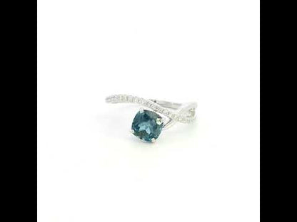 18K white gold twist ring featuring a 1.10 carat natural cushion-cut London Blue Topaz with a diamond-set crossover band and 0.15 carat natural diamonds.
