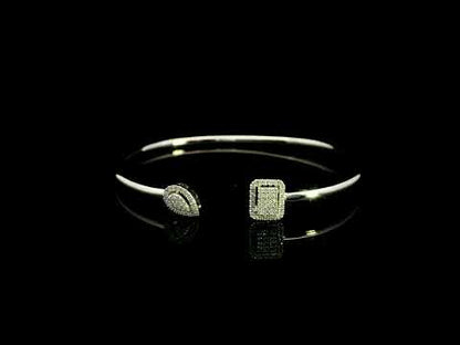 Geometric diamond open bangle in 18K white gold with contrasting pear-shaped and rectangular diamond motifs.