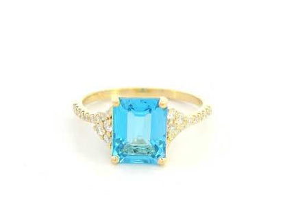 Emerald-cut blue topaz and diamond ring in 18K yellow gold by Emirates Diamonds.