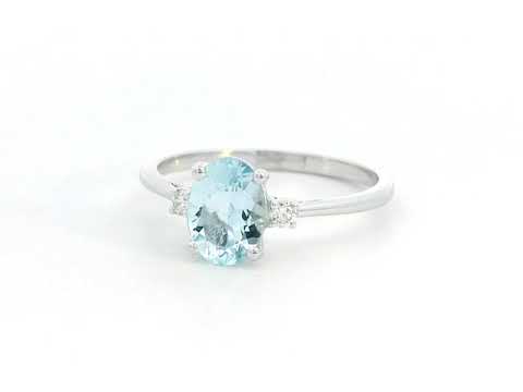 Oval Aquamarine and diamond ring in 18K gold, featuring a 0.93ct blue gemstone flanked by round-cut diamonds. 