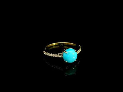 18K yellow gold turquoise and diamond ring featuring a round cabochon turquoise gemstone in a four-prong setting with round diamonds along the band.