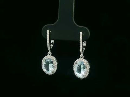 18K gold drop earrings with oval aquamarine center stones and diamond halo design


