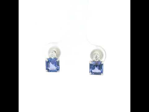 Pair of 18K white gold tanzanite and diamond stud earrings featuring square emerald-cut blue-violet tanzanites with a round diamond accent above each gemstone.