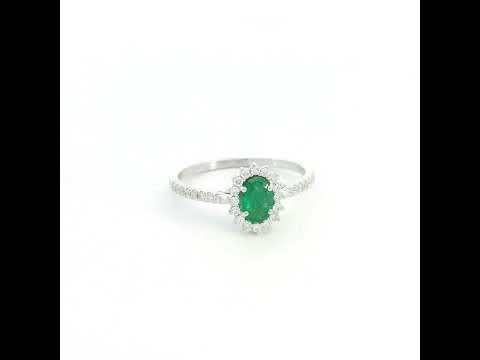 Natural oval emerald ring in 18K white gold featuring a 0.35 carat emerald surrounded by a diamond halo with 0.23 carat total diamond weight.