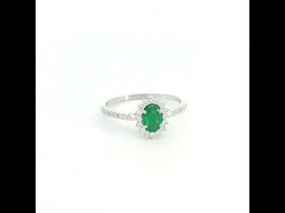 Natural oval emerald ring in 18K white gold featuring a 0.35 carat emerald surrounded by a diamond halo with 0.23 carat total diamond weight.