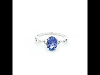 Oval tanzanite solitaire ring with sculptural crossover band in 18K white gold.