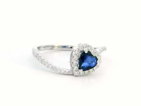 Heart-cut blue sapphire ring with diamond halo set in 18K gold, featuring a bypass design for a romantic touch.