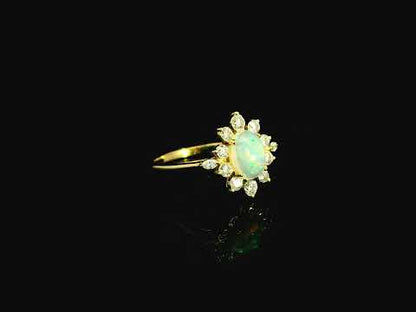Oval opal diamond halo ring in 18K yellow gold with sunburst cluster design Emirates Diamonds