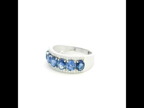 Blue sapphire and diamond band ring in 18K white gold featuring oval blue sapphires framed by two rows of sparkling diamonds, worn on a hand.