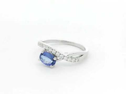 18K white gold tanzanite ring featuring a 0.70 carat oval-cut tanzanite and 0.23 carats of natural diamonds in a crossover design.