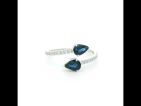 18K white gold blue sapphire Toi et Moi ring featuring two pear-shaped blue sapphires positioned in opposite directions with round diamonds along the open band.