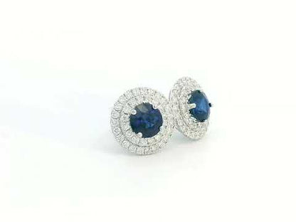 Round Sapphire and Diamond halo stud earrings in 18K white gold, featuring 2.27 carats of deep blue Sapphire and 0.81 carats of sparkling Diamonds.