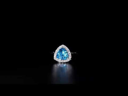 18K white gold ring with a triangular bright blue topaz surrounded by round diamonds and polished split-shank shoulders.