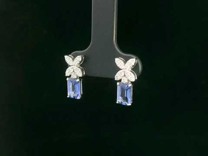 18K white gold earrings featuring emerald-cut Tanzanites beneath floral diamond clusters, total 1.56 carat