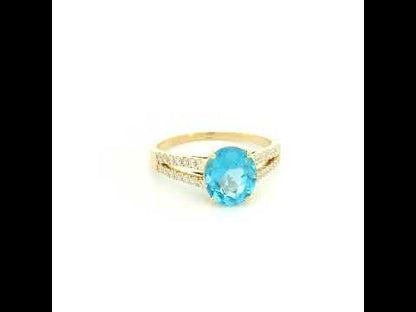 18K yellow gold Swiss blue topaz ring with oval centre stone and double-row diamond split shoulders.