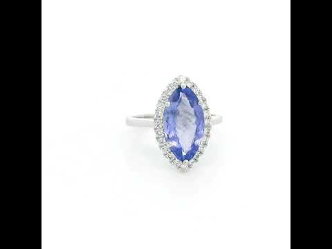 Marquise tanzanite and diamond halo ring in 18K white gold featuring a blue-violet gemstone surrounded by round diamonds.