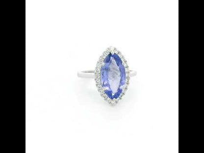 Marquise tanzanite and diamond halo ring in 18K white gold featuring a blue-violet gemstone surrounded by round diamonds.