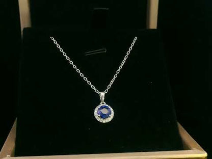 "18K white gold sapphire and diamond halo pendant featuring a 0.72ct deep blue sapphire surrounded by a 0.10ct diamond halo, 