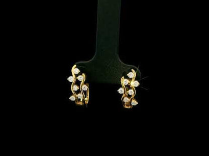 18K yellow gold diamond wave hoop earrings featuring flowing open gold curves with scattered round brilliant diamonds.