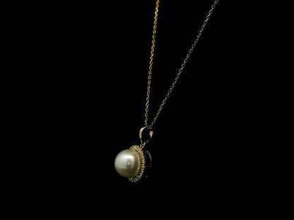 Freshwater white pearl and diamond halo pendant in 18K yellow gold with a round pearl surrounded by brilliant diamonds.
