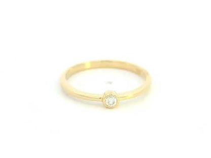 18K yellow gold bezel set diamond ring featuring a 0.07 carat natural round brilliant diamond in a minimalist solitaire design.