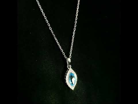 Blue topaz and diamond halo pendant in 18K white gold featuring a 0.70 carat oval blue topaz surrounded by 0.15 carat round diamonds in an elongated marquise-shaped setting, shown with a chain for display.