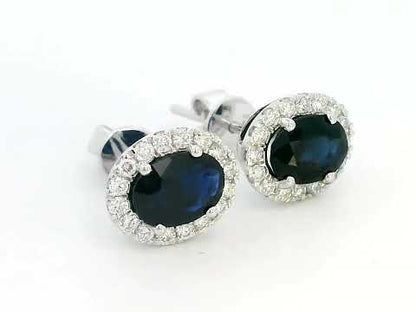 18K gold stud earrings featuring 1.88 carat oval blue sapphires and a 0.33 carat diamond halo, perfect for September birthstone jewelry.