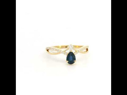 Pear shaped blue sapphire and diamond ring in 18K yellow gold with sweeping diamond-set design.