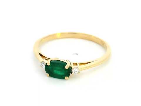 18K yellow gold oval emerald and diamond ring featuring a 0.59-carat emerald with 0.05-carat round diamonds on each side in a classic four-prong setting.