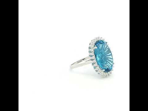 Swiss Blue Topaz halo ring in 18K white gold with an oval blue gemstone surrounded by round diamonds.