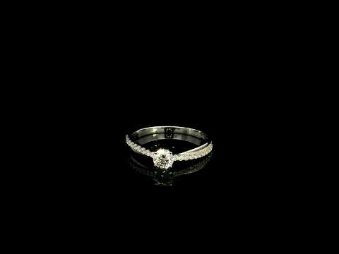 18K white gold minimalist engagement ring featuring a round brilliant diamond with an asymmetrical crossover band and pavé diamonds.