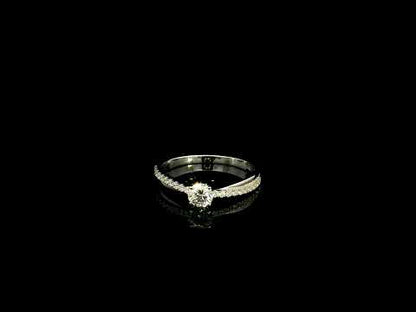 18K white gold minimalist engagement ring featuring a round brilliant diamond with an asymmetrical crossover band and pavé diamonds.