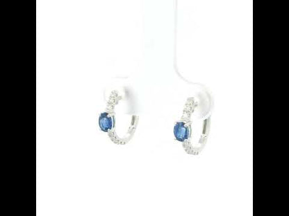 18K white gold blue sapphire and diamond huggie hoop earrings featuring oval blue sapphires and diamond-set hoops.