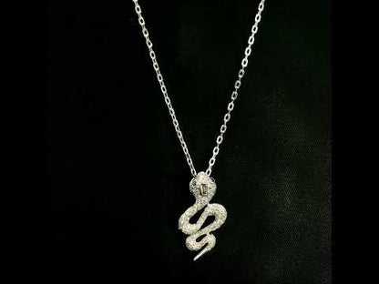 18K white gold snake pendant necklace featuring a curved serpent with round diamonds along its coiled body, a detailed head and a polished tapered tail.