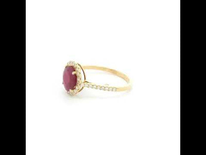 Ruby and diamond halo ring in 18K yellow gold featuring a round red ruby surrounded by diamonds with diamond-set shoulders.