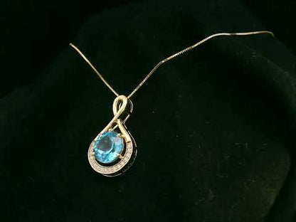 18k yellow gold pendant with 2.30 carat Swiss blue topaz center, diamond halo, and infinity-style bale