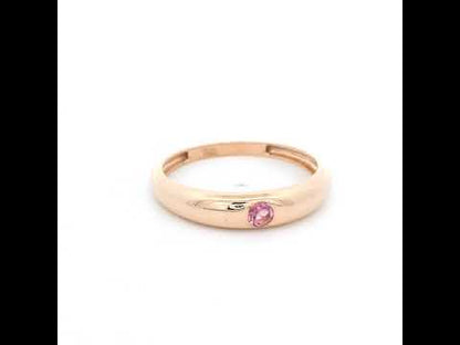 Pink tourmaline ring in 18K rose gold featuring a small round pink gemstone set into a smooth, polished, rounded gold band.