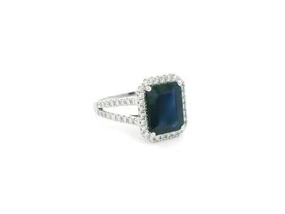 Emerald cut blue sapphire halo ring in 18K white gold with diamond split band Emirates Diamonds