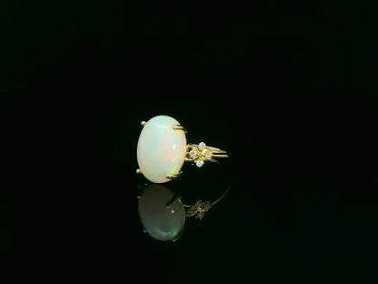 Oval cabochon opal ring in 18K yellow gold with diamond accents by Emirates Diamonds