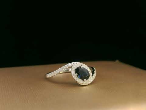Oval blue sapphire halo ring with pavé diamonds in 18K white gold, bypass design